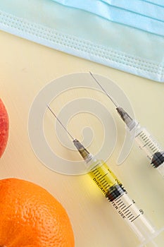 Chemical additives in food or genetically modified fruit concept.  Red apple with syringes of chemicals. Isolated on red backgroun