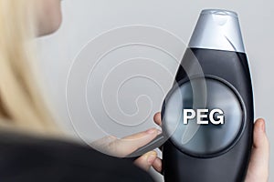 Chemical components on the shampoo label: PEG. A hand holds jar and a magnifier, where the harmful ingredients of a detergent are photo