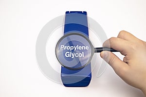 Chemical components on the shampoo label: Propylene Glycol. A hand holds a blue jar and a magnifier, where the harmful ingredients photo
