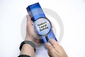 Chemical components on the shampoo label:  Sodium Lauryl Sulfate sls, sles. A hand holds a blue jar and a magnifier, where the