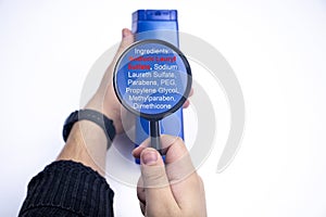 Chemical components on the shampoo label:  Sodium Lauryl Sulfate sls, sles. A hand holds a blue jar and a magnifier, where the