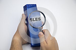 Chemical components on the shampoo label:  Sodium Lauryl Sulfate sls, sles. A hand holds a blue jar and a magnifier, where the photo