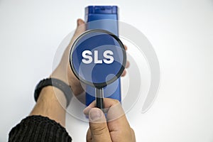 Chemical components on the shampoo label:  Sodium Lauryl Sulfate sls, sles. A hand holds a blue jar and a magnifier, where the photo