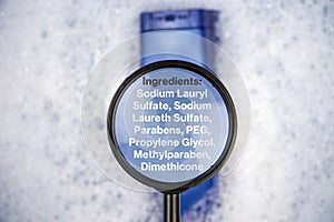 Chemical components on the shampoo label:  Sodium Lauryl Sulfate sls, sles. A hand holds a blue jar and a magnifier, where the photo