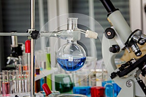 Chemical distillation glasses with microscopes placed in a laboratory with red, orange, blue chemicals in the beaker