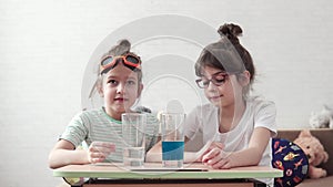 Chemical experiment. Children are engaged in elementary chemistry at home. the elder sister explains the basics of
