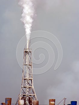 Chemical factory polluting air, closeup of tower.