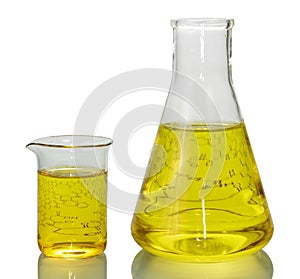 A chemical flask, a beaker with yellow liquids and a sheet of pa