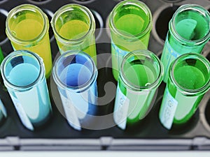 Chemical flasks with multi-colored solutions inside, isolated on white background, set on a black stand