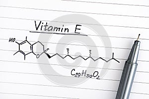 Chemical formula of Vitamin E on lined paper with pen.