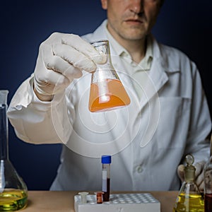 Chemical formulation for medicine, laboratory research. The laboratory assistant holds a flask in his hand.