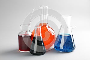 Chemical glassware with colorful liquids on light background