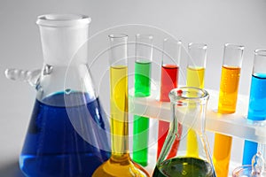 Chemical glassware with colorful samples on light background, closeup