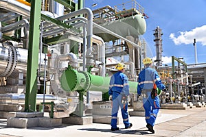 Chemical industry plant - workers in work clothes in a refinery with pipes and machinery