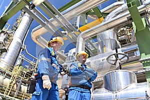 Chemical industry plant - workers in work clothes in a refinery with pipes and machinery