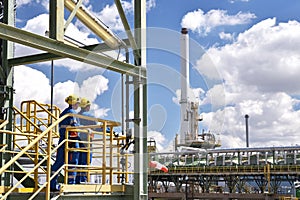 chemical industry plant - workers in work clothes in a refinery with pipes and machinery