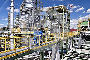 chemical industry plant - workers in work clothes in a refinery with pipes and machinery