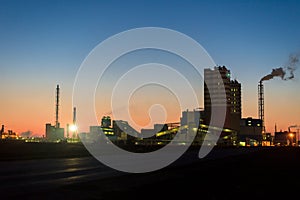 Chemical plant in a silhouette image at sunset, the glowing light of the chemical industry at sunset and twilight sky, the field
