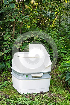 Chemical portable toilet. Single portable toilet standing on green nature courtyard background