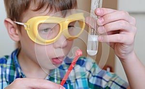 Experiments on chemistry at home. Closeup boy`s face. Chemical reaction with the release of gas in a test tube in the