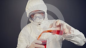 Chemical scientist in protective clothing mixing chemical liquids.