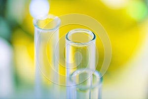 Chemical test tubes against the background of a large glass chemical flask with yellow liquid