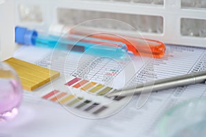 Chemical test tubes with blue and orange liquid with analysis results on table closeup