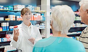 Chemist advising senior couple on a drug in her pharmacy