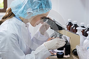 Chemist analyzing sample under microscope in laboratory of cosme