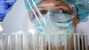 Chemist checking test tube with blue liquid, perfumes development, cosmetology