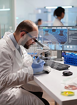 Chemist doctor looking through microscope at virus sample