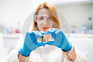 Chemist in goggles shaking test tubes with blue and yellow solution