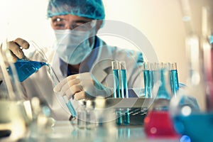 Chemist manipulating a liquid from beaker to a tube