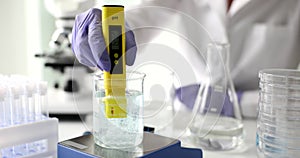 Chemist measuring acidity of liquid in glass using pH meter in lab closeup 4k movie slow motion