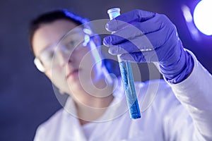 Chemist`s hand holding test tube with blue liquid