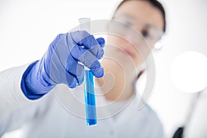 Chemist`s hand on white background holding test tube with blue liquid