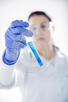 Chemist`s hand on white background holding test tube with blue liquid