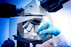 Chemist and samples with microscope and rubber gloves. Medical chemist in pharmaceutical field examining