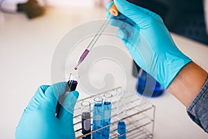 Chemist scientist conducts experiments by synthesising compounds with using dropper in a test tube