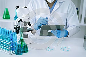 Chemist scientist holding test tube and tablet conducting experiment in laboratory with equipment, science concept