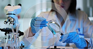 Chemist studies contents of test tube using magnifying glass