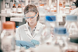 Chemist wearing safety glasses and using tablet pc