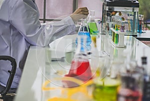 Chemist works at the laboratory, morning room has sunlight shining through, With test specimens working with colorful liquid photo