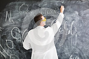 Chemist write a chemical formula on blackboard.