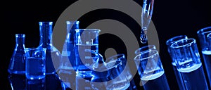 Collage of different laboratory glassware with liquids on black background