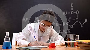 Chemistry experimenter writing down results of scientific researches in lab