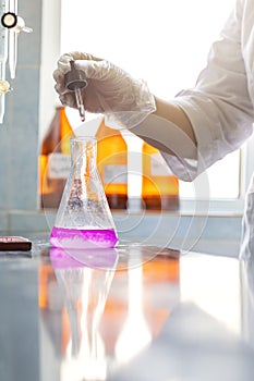 Chemistry expert is working with solutions and test tubes on the workbench in a chemistry laboratory.