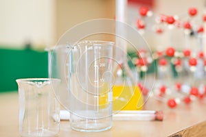 Chemistry glassware with liquid formula and molecular structure model at the science classroom laboratory.