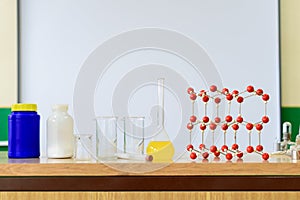 Chemistry glassware with liquid formula and molecular structure model at the science classroom.
