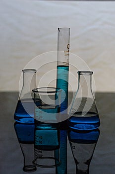 Chemistry Laboratory glassware tools on a reflecting surface